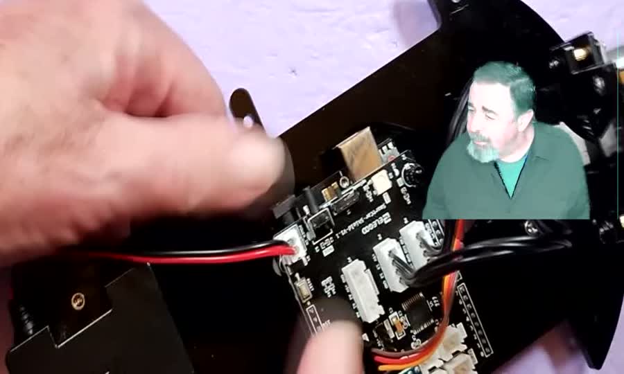 The red-and-black battery wire being pushed onto its connector on the car's board